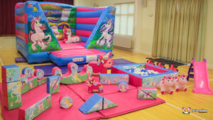 Unicorn themed bouncy castle with rainbows and matching soft play. themed ball pool